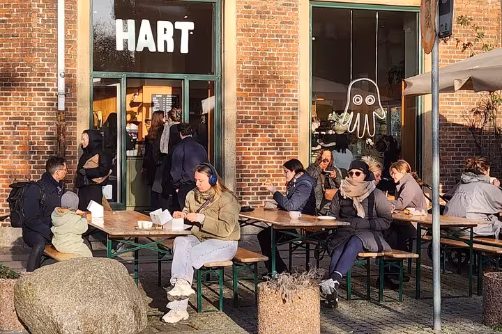 Visitors enjoying coffee outside a cozy Copenhagen cafe, embracing Danish hygge and local culture.