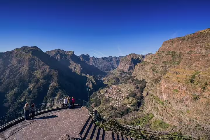 Tourists admire the breathtaking panoramic view of Nun's Valley from a scenic lookout point in Madeira.