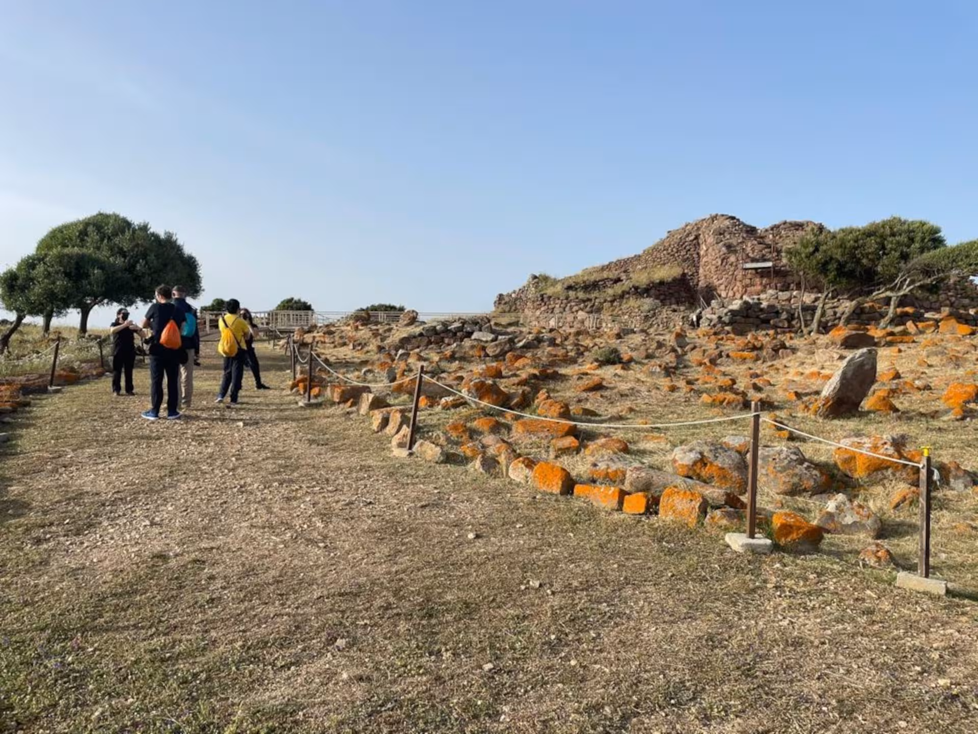 Tourists explore the historic Nuraghe Seruci site in Gonnesa, surrounded by ancient stone structures and scenic views.