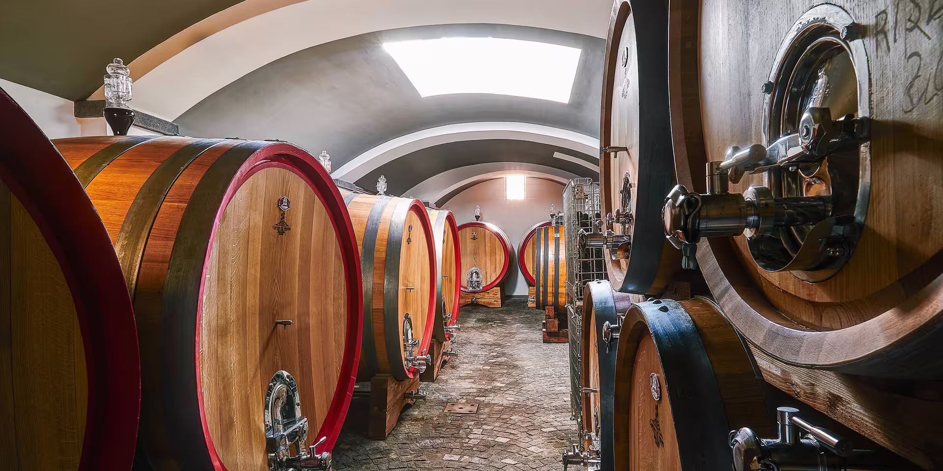 Oak wine barrels in a vaulted cellar, part of the Wine Tasting Luxury & Portici Palace experience