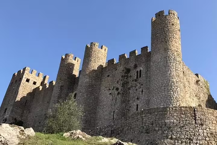 Medieval Óbidos Castle under a clear blue sky, a highlight of the Fátima, Nazaré, and Óbidos full-day tour in Portugal.