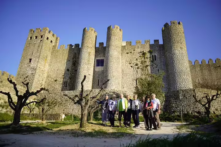 Tourists explore the historic Óbidos Castle on a sunny day during a full-day private tour from Lisbon, Portugal.