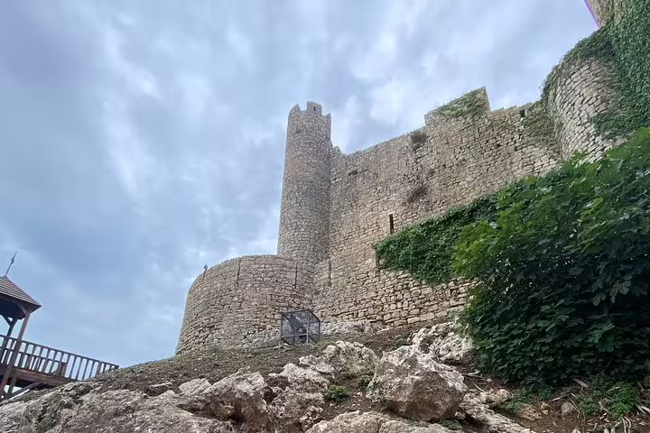 View of the medieval Óbidos Castle walls under a cloudy sky, part of the Lisbon to Óbidos tour experience.