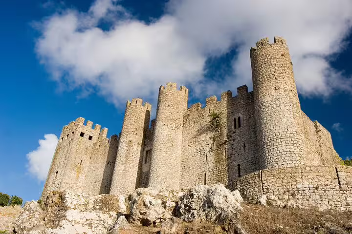 Majestic view of Obidos Castle under a vibrant blue sky, a highlight on the private tour to Obidos, Nazare, and Alcobaca.