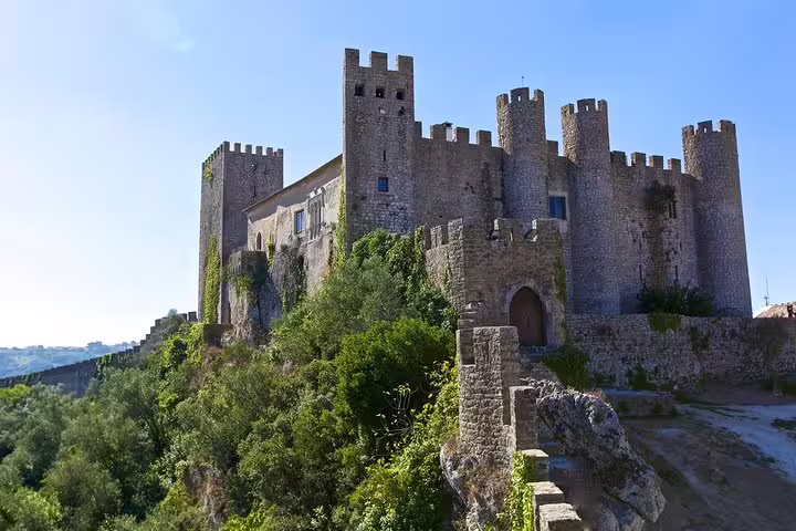 Medieval castle in Óbidos, Portugal, surrounded by lush greenery, featured in the Fatima Nazare and Obidos Private Full Day Tour.