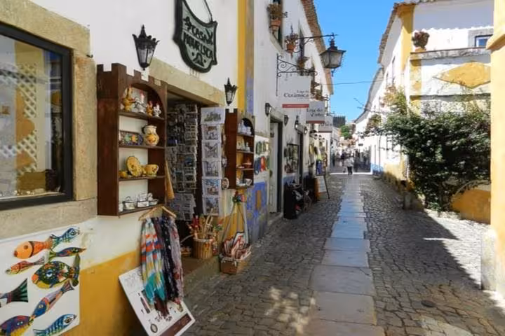 Charming cobblestone street in Óbidos lined with colorful shops offering local crafts and souvenirs.