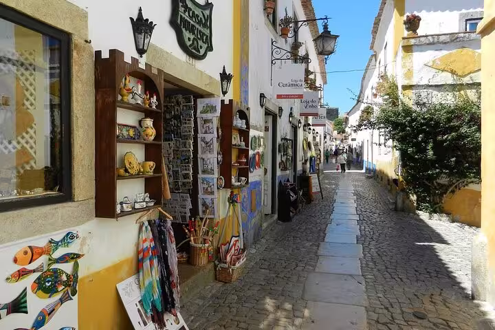Charming cobblestone street in Óbidos lined with colorful shops, perfect stop on Lisbon to Porto private transfer.