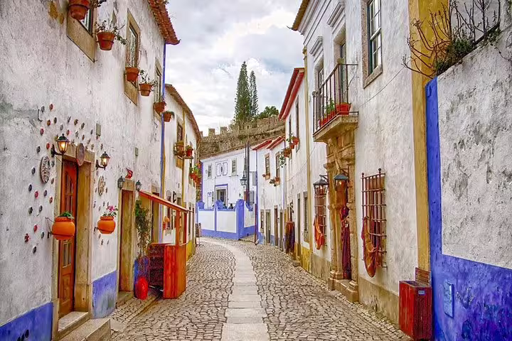 Charming cobblestone street in Óbidos, Portugal, showcasing colorful buildings and historic architecture on a private full-day tour.