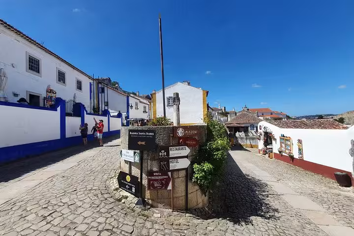 Charming cobblestone street in Óbidos with directional signs, showcasing the historic and picturesque allure of Portugal's small-group tours.