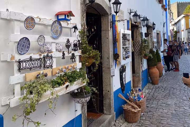 Charming cobblestone street in Óbidos with traditional Portuguese ceramics, a highlight of the Lisbon guided tour.