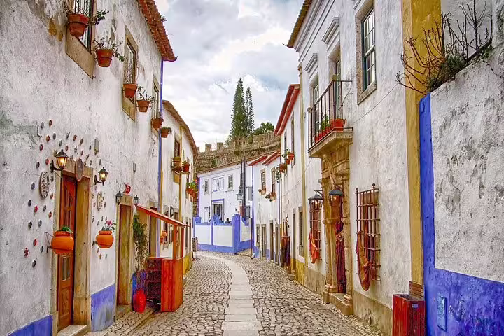 Charming cobblestone street in Óbidos, Portugal, showcasing colorful historic buildings ideal for a private tour of Óbidos, Nazaré, and Alcobaça.