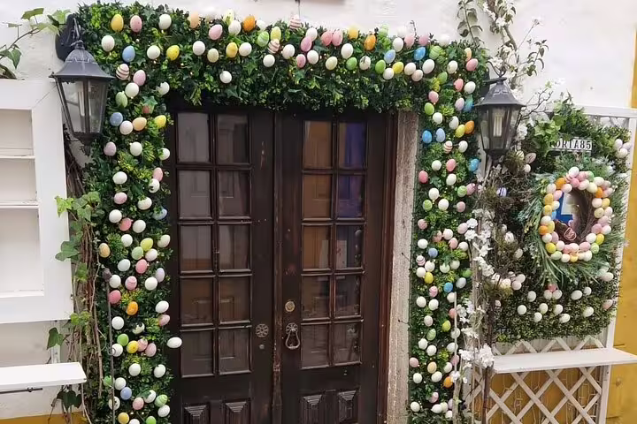 Festive doorway in Óbidos adorned with vibrant egg decorations and lush greenery, capturing local charm.
