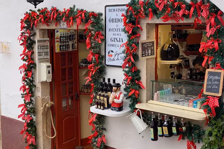 Charming Obidos shop adorned with festive garlands, showcasing local Ginja liqueur bottles on Lisbon to Obidos tour.