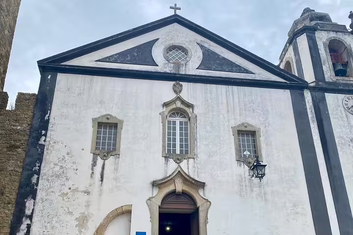 Front view of a historic church in Óbidos with classic architectural details, showcasing cultural landmarks on the tour.