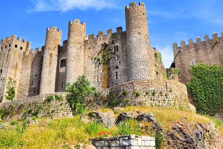 Majestic medieval castle in Óbidos under a clear blue sky, part of the Lisbon small group day tour to Fátima, Nazaré, and Óbidos.