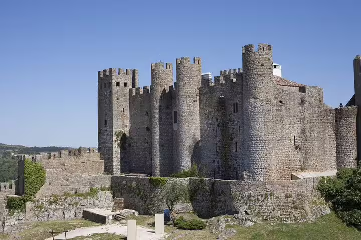 Majestic medieval castle in Óbidos under clear skies, a highlight of the Óbidos and Nazaré tour from Lisbon.