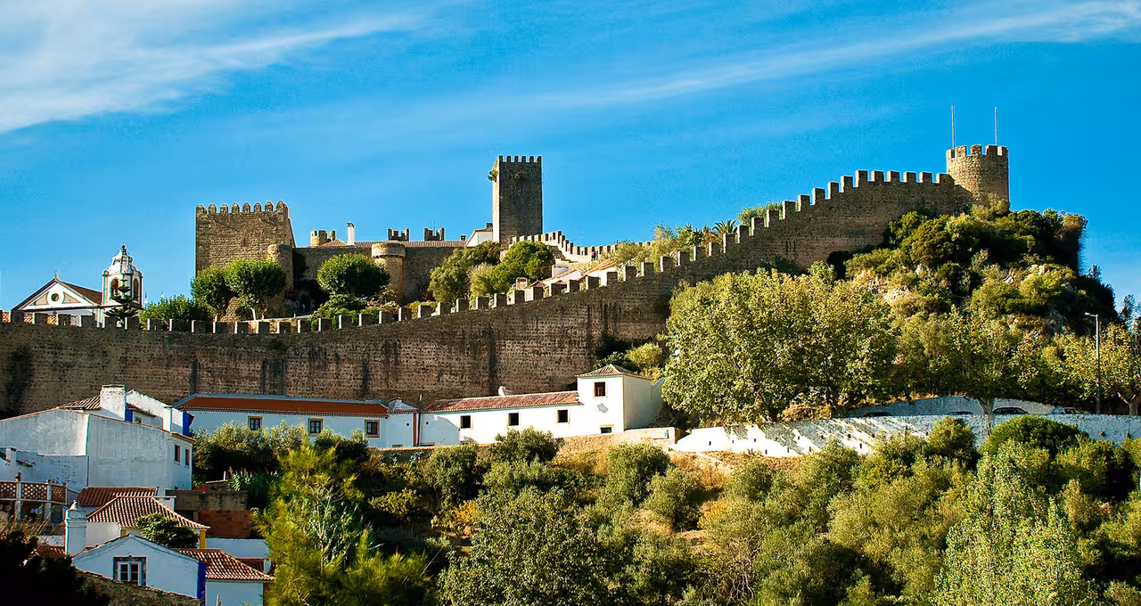 Scenic view of Óbidos' medieval castle walls surrounded by lush greenery, perfect for a full day private wine tour experience.
