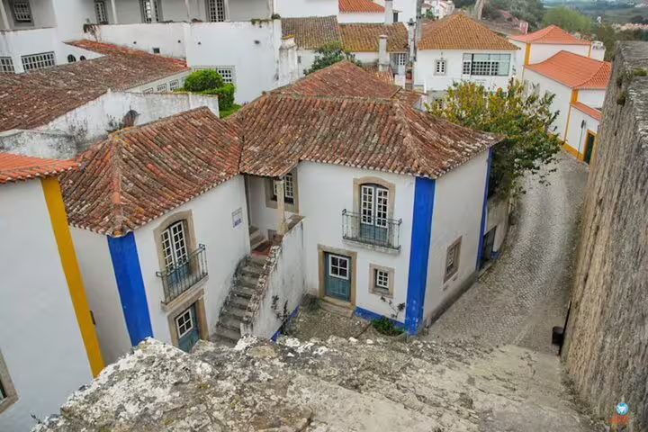 Charming medieval street view in Obidos with traditional whitewashed houses and cobblestone paths.