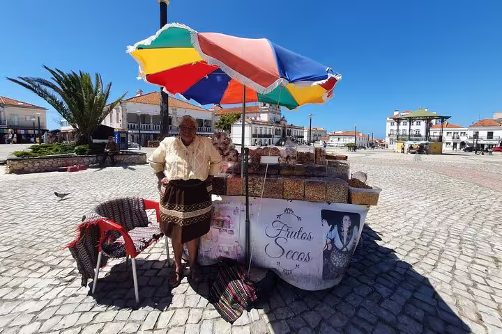 Local vendor selling traditional dried fruits under a colorful umbrella in Óbidos, Portugal, during a sunny private tour.