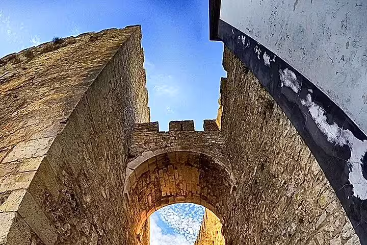 Ancient stone archway in Óbidos, Portugal, featuring historic architecture under a vibrant blue sky on a full-day tour from Lisbon.