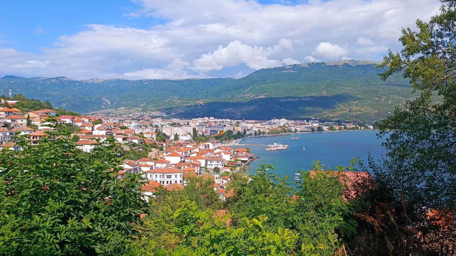 Scenic view of Ohrid Lake with red-roofed houses and lush mountains, perfect for Balkan tour adventures.