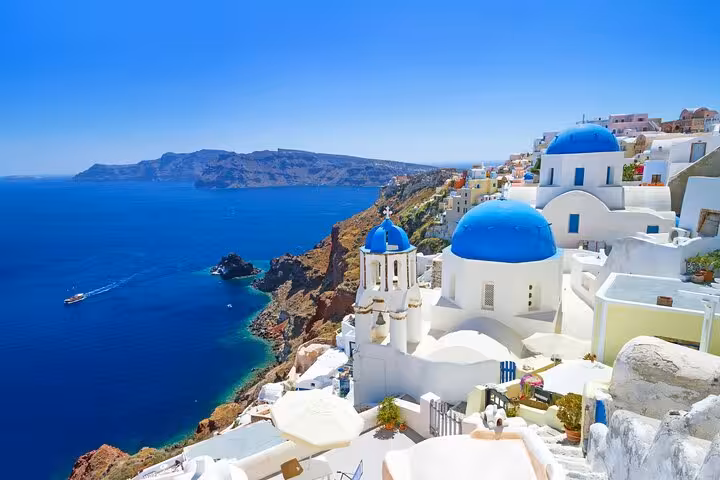 Oia blue-domed churches overlooking the Santorini caldera, highlight stop on Oia Pyrgos Imerovigli tour