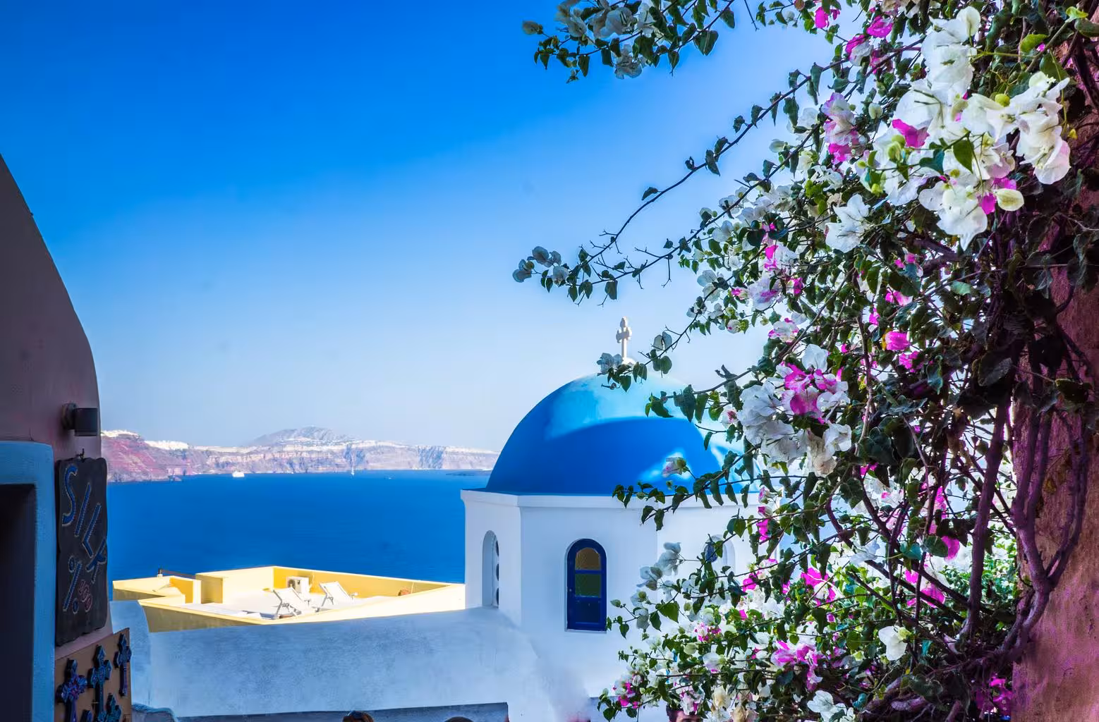 Blue-domed Oia church and bougainvillea with caldera sea views on a semi-private Santorini panoramic tour