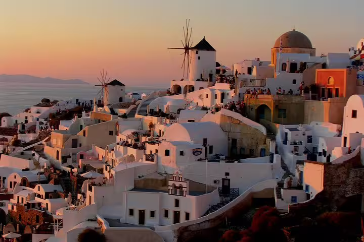 Oia Santorini sunset with iconic windmills and whitewashed houses, featured on a 3-day private tour from Athens