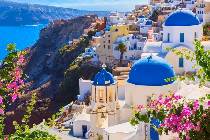 Oia village cliffside with blue domes and bougainvillea, Santorini day trip from Crete private tour