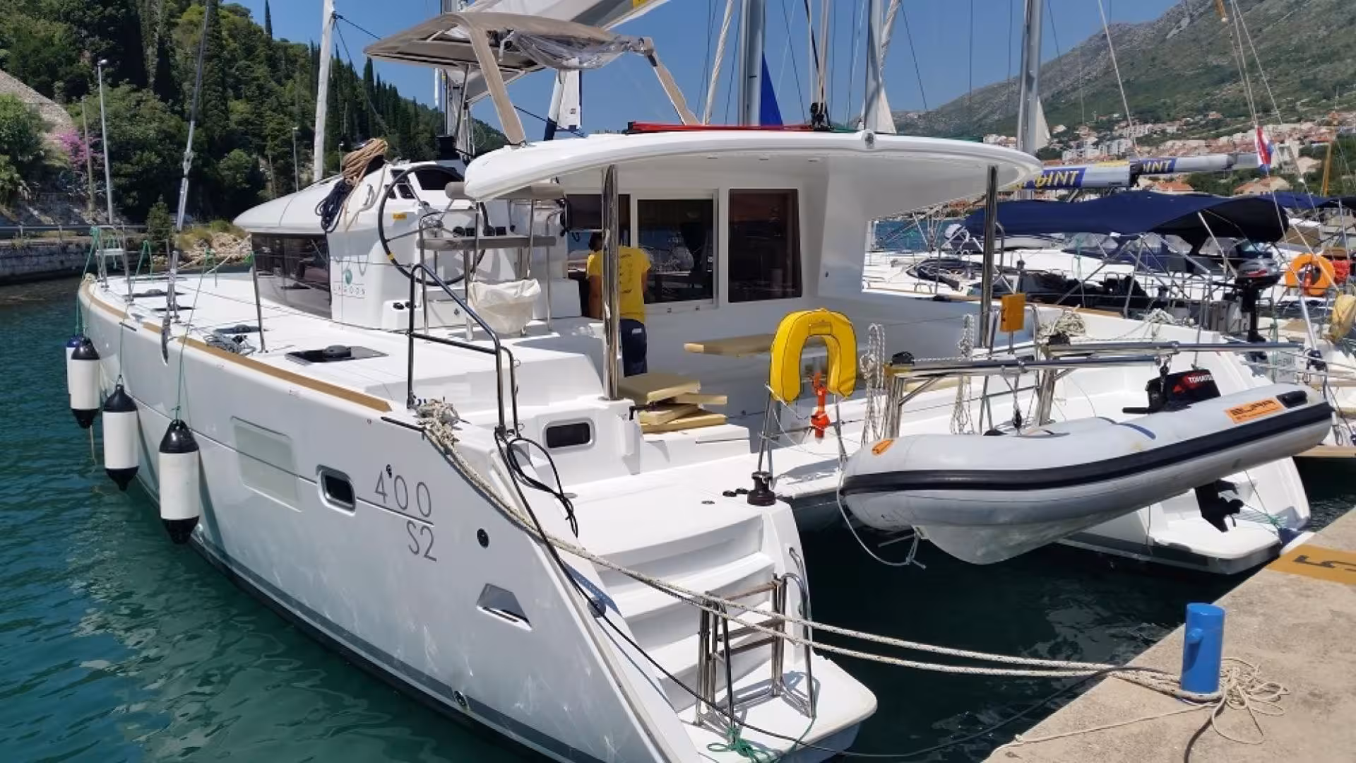 Docked catamaran in Olbia, featuring spacious deck and dinghy, ideal for Tavolara Marine Area exploration.