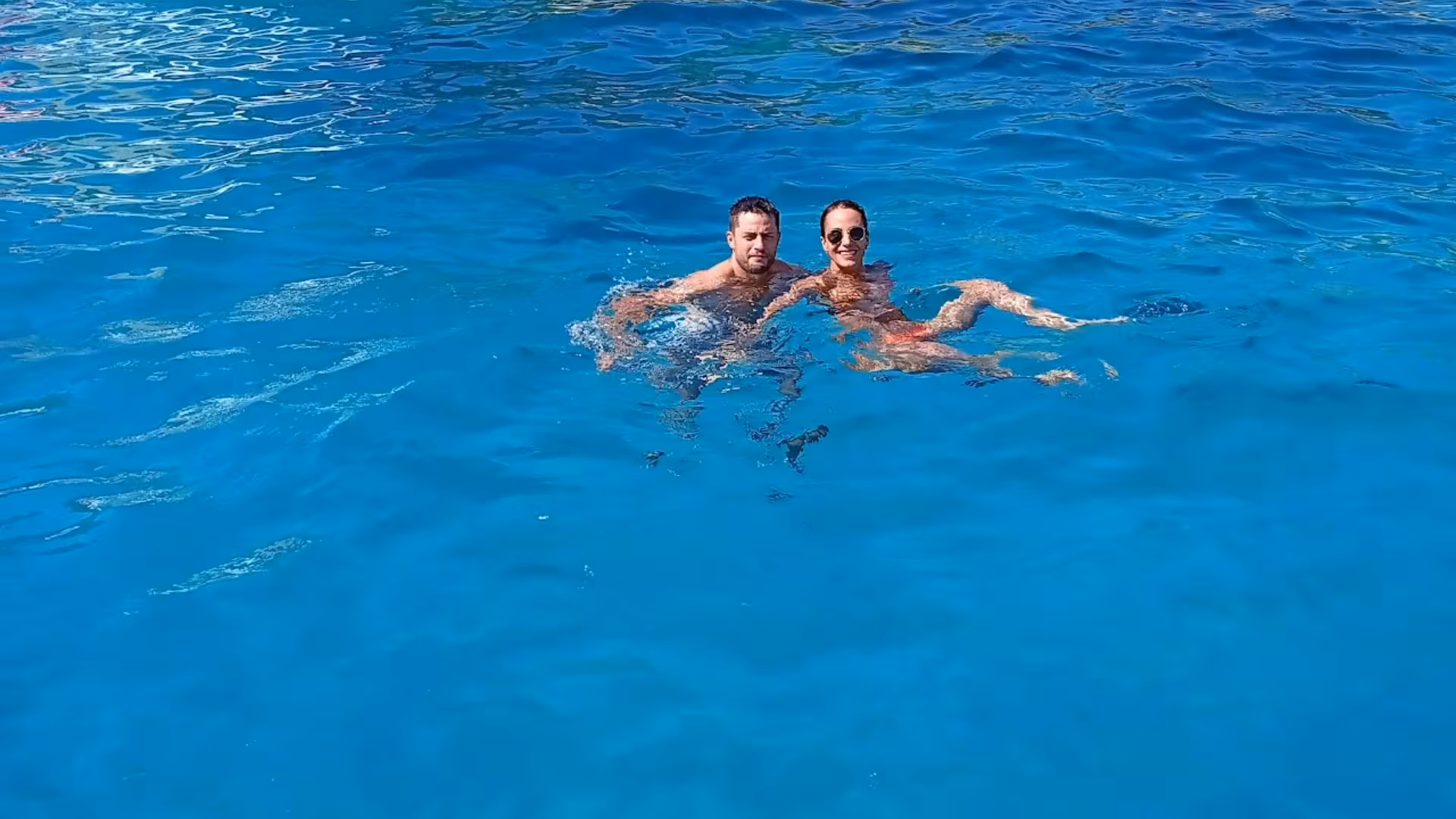 Two people swimming in crystal-clear blue waters near Capo Figari during Olbia dolphin watching RIB tour.