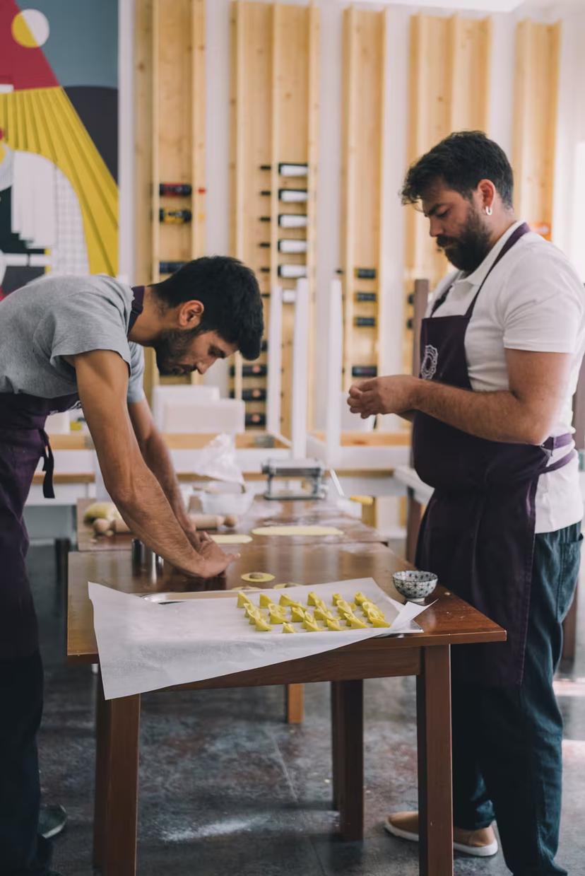 Two men crafting pasta from scratch in an Olbia workshop, featuring fresh ingredients and traditional Italian techniques.