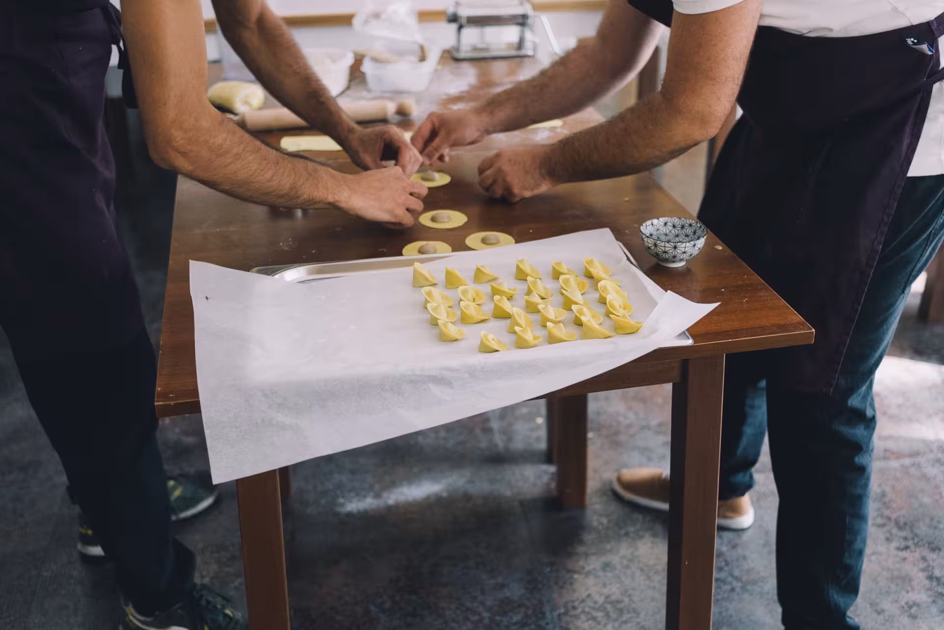 Hands-on pasta workshop in Olbia with participants crafting fresh tortellini on a wooden table.