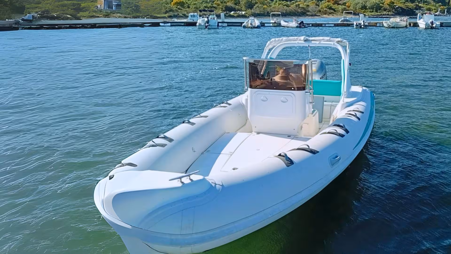 White RIB boat anchored in clear waters at Cugnana, perfect for Olbia tours to Capriccioli and Spiaggia del Principe.