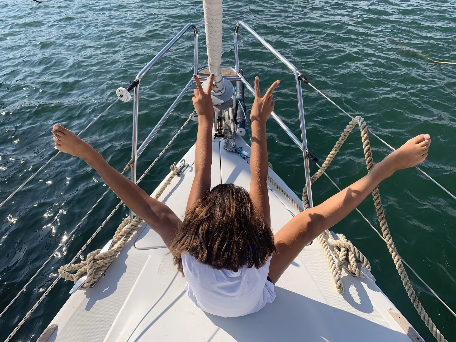 Person relaxing on a sailboat in clear waters near Tavolara during an Olbia sailing tour.