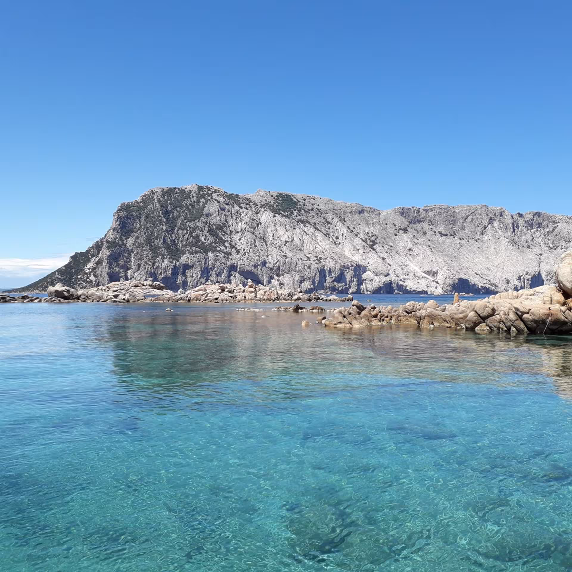 Clear turquoise waters with rocky Tavolara Island backdrop on Porto San Paolo boat tour.
