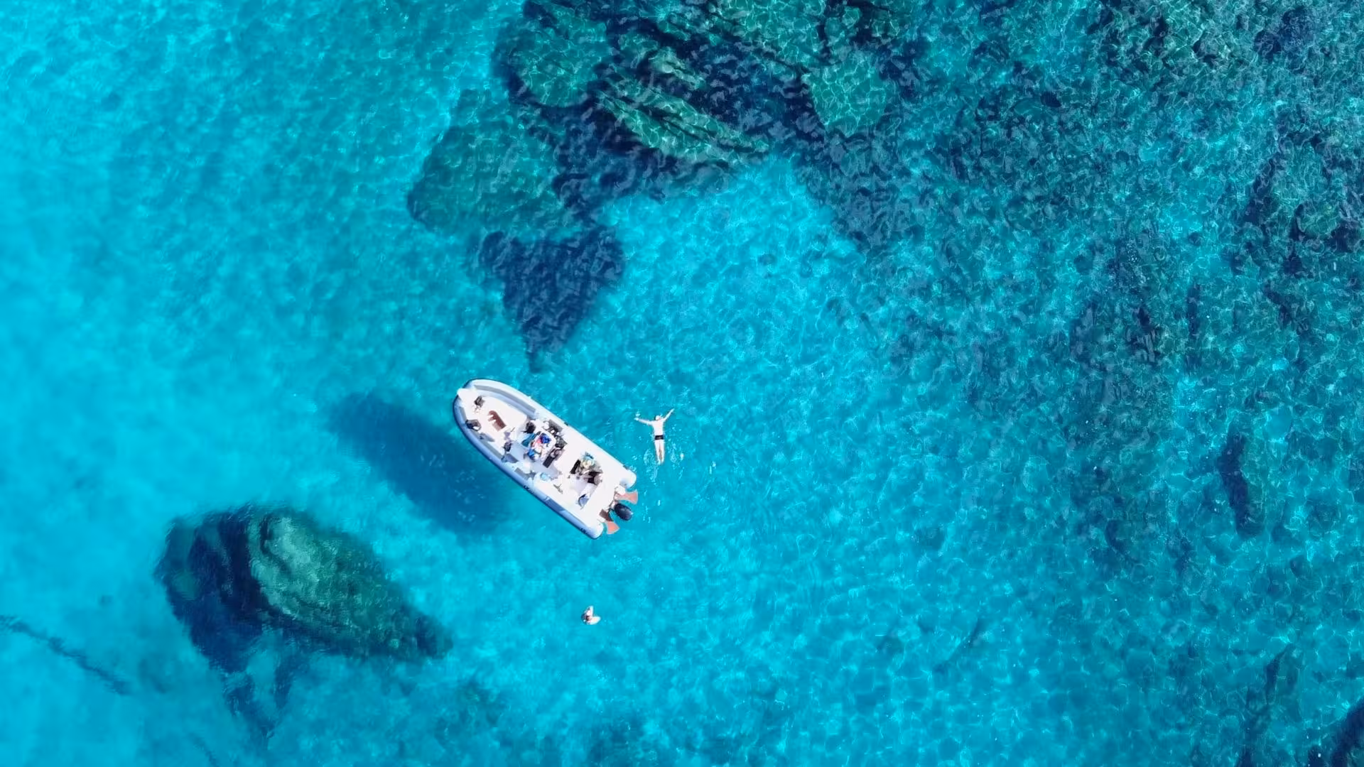 Aerial view of a dinghy tour near Tavolara with snorkelers exploring the crystal-clear waters from Olbia.