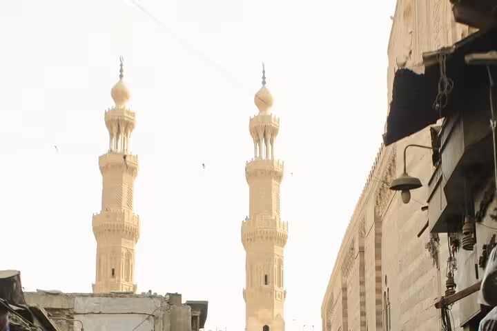 Twin mosque minarets rising over Old Cairo alley, highlighting Islamic architecture on a medieval Cairo tour