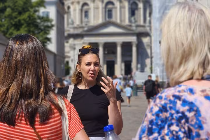 Tour guide explains the history of Old Copenhagen to attentive visitors near a historic building under sunny skies.