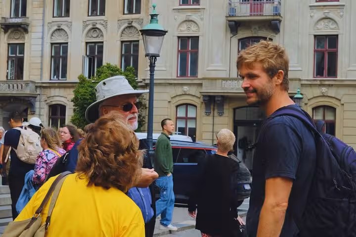 Tourists engage in conversation with a guide in Old Copenhagen, surrounded by historical architecture.