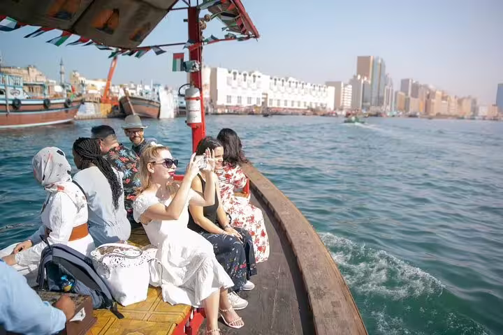 Small group of tourists enjoying a traditional abra boat ride on Dubai Creek during a guided walking tour of Old Dubai