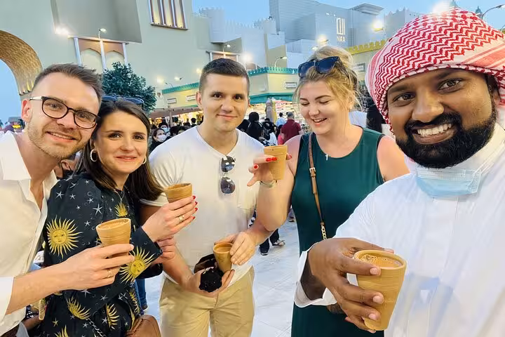 Tour guests enjoy Arabic coffee in Old Dubai market on local food 6 tastings walking tour with guide