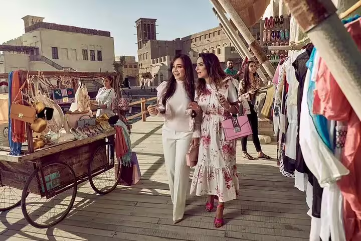 Visitors explore vibrant market stalls in Old Dubai, experiencing the rich culture and shopping on a private tour.