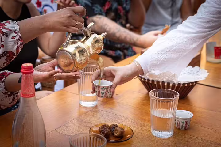 Guests sample Arabic coffee and fresh dates served in traditional cups on a cultural walking tour with local snacks in Dubai