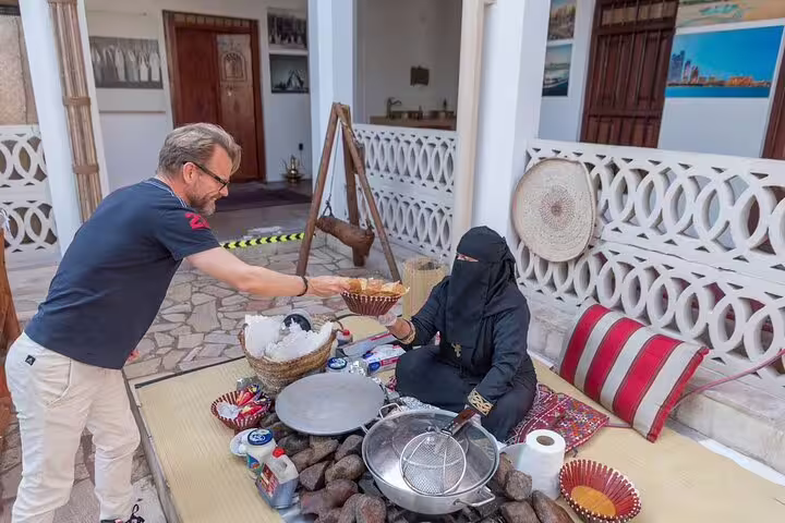 Visitor sampling traditional Emirati snacks from a local vendor during a guided walking food tour in historic Old Dubai