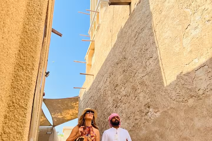 Travelers exploring Al Fahidi historical district lanes on Old Dubai walking tour with tastings and abra ride