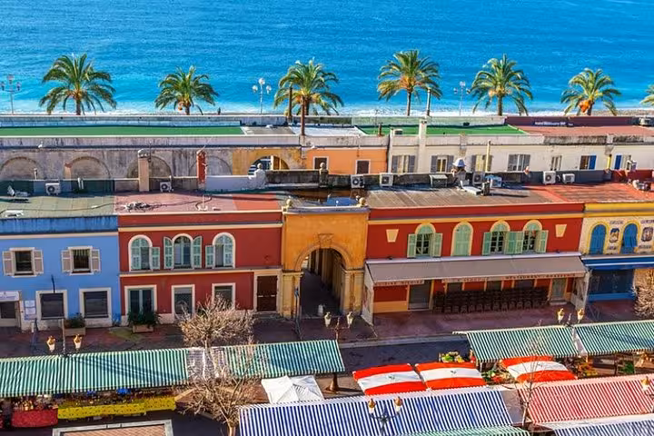 Colorful buildings and palm-lined promenade overlooking the Mediterranean Sea in Old Town Nice, France, a scenic tour highlight.