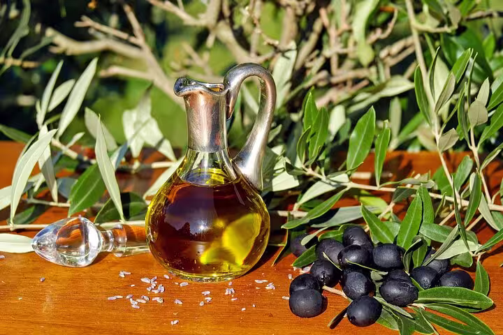 A fresh olive oil decanter with black olives and green branches, showcasing Cordoba's authentic oil tasting experience.