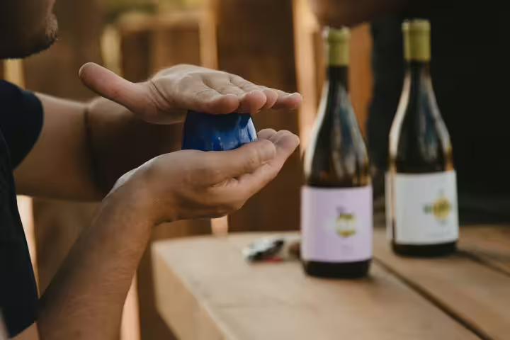 Person sampling olive oil at an outdoor tasting event with regional products in the scenic countryside setting.