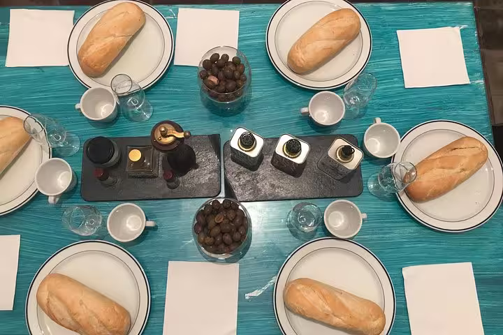 Table set for olive oil tasting in Cordoba with fresh baguettes, olives, and premium olive oil bottles.